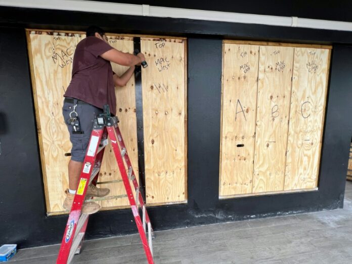 A man boards up a store in Hamilton