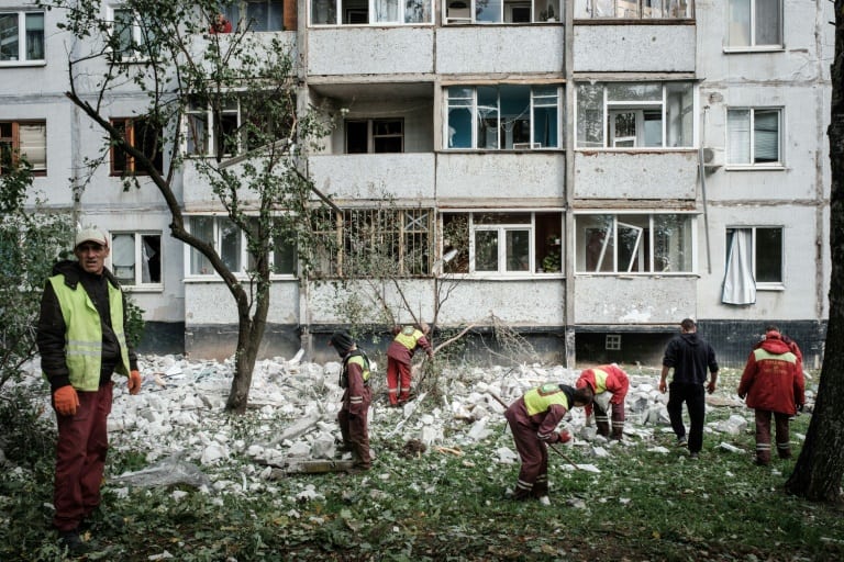 Workers remove debris from a residential building hit