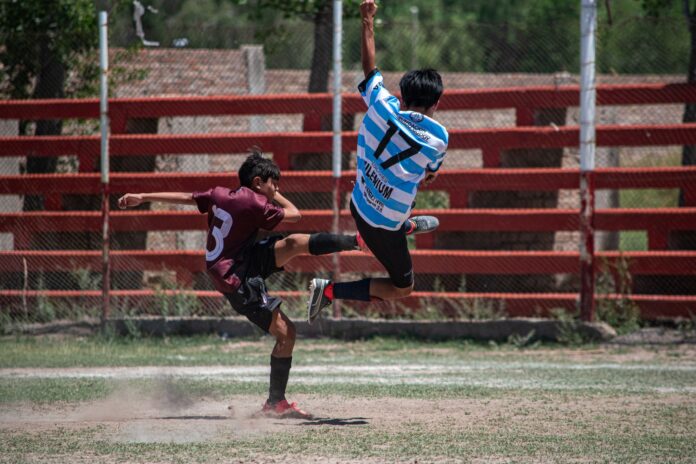 Intense soccer tackle captured during a youth match on a sunny day.