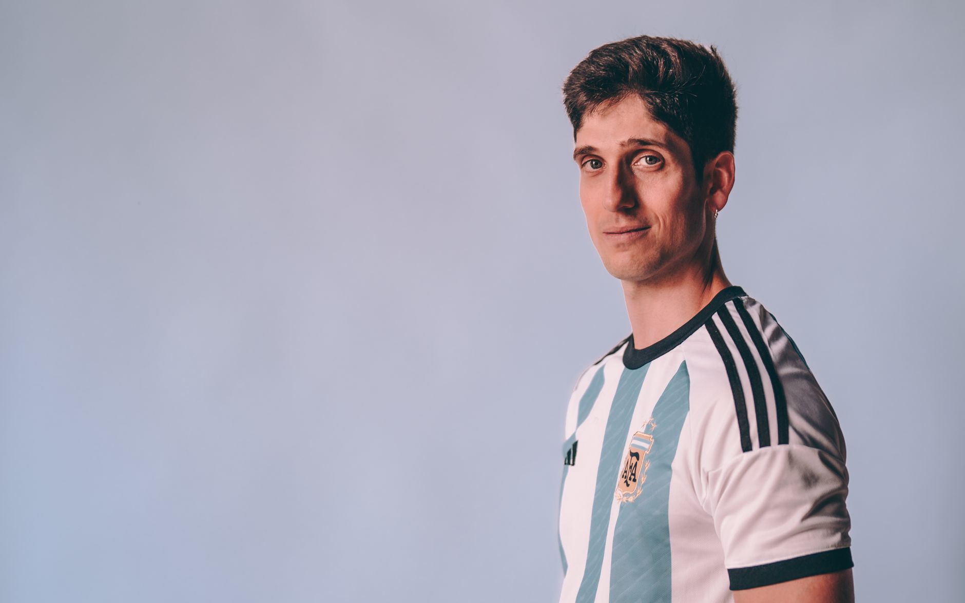 Portrait of a young man in an Argentina soccer jersey with a calm expression.