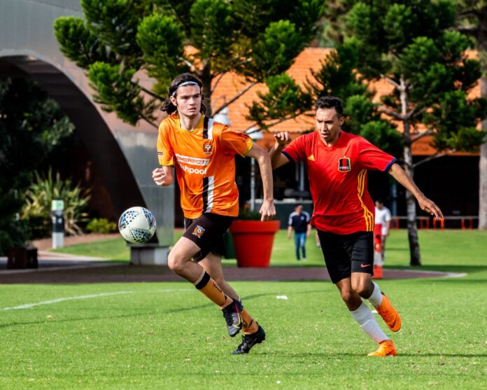 Two soccer players in action outdoors, showcasing competitive sportsmanship on a sunny day.